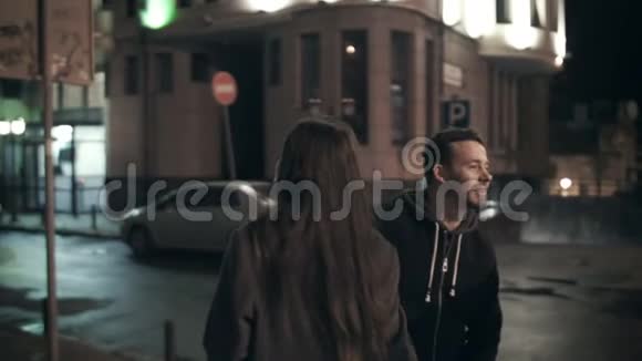 一对夫妇牵着手穿过马路穿过夜城的街道视频的预览图