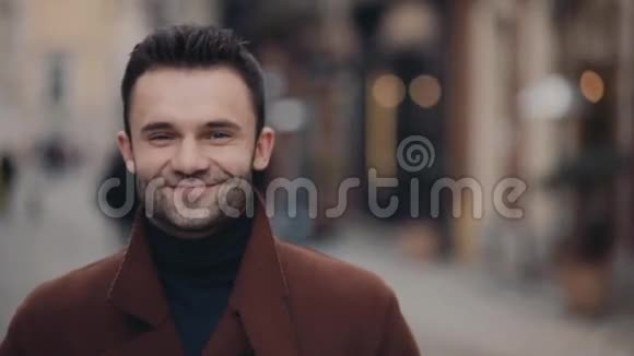 英俊的年轻人穿着休闲的棕色外套站在市中心镜头灿烂地微笑玩得开心视频的预览图