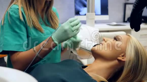 坐在牙医椅上的一名女性病人和一名女性牙医用X光拍摄病人的牙齿视频的预览图