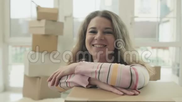 快乐的女人倚在打开的盒子上视频的预览图