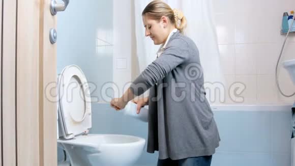 一位年轻女子在做家务时在厕所里倒抗菌洗涤剂的4K镜头视频的预览图