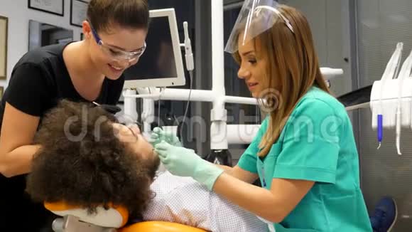 一位女牙医和她的助手检查一位年轻人牙齿的照片视频的预览图