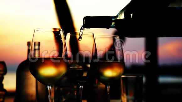 在令人惊叹的日落时分在海滩餐厅的海景中缓慢地在玻璃中倒入白酒快关门1920x1080视频的预览图