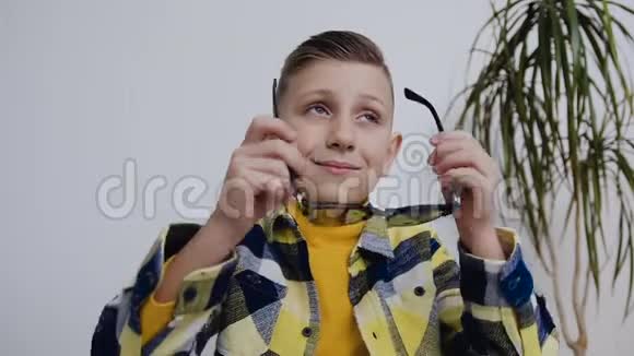 一个蓝眼睛的英俊小男孩戴着太阳镜看着一边在房间里白色背景视频的预览图