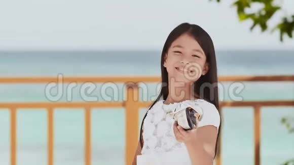 菲律宾女学生穿着白色连衣裙微笑吃着脆脆的薯片热带景观手掌夏天视频的预览图