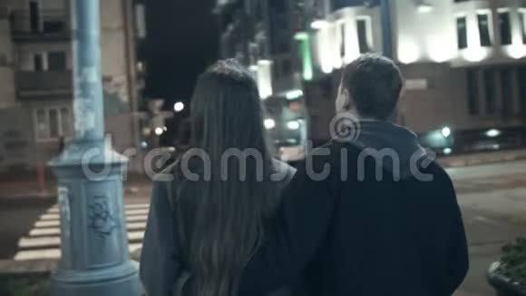 这对夫妇晚上从摄像机旁走在人行横道上过马路视频的预览图