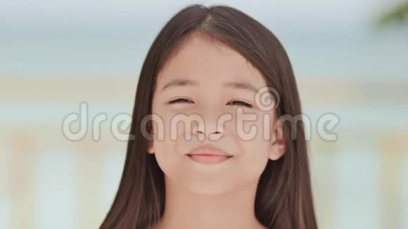 一位迷人的菲律宾女学生正摆姿势在热带海滩的白色蓝色背景上进行面部特写视频的预览图