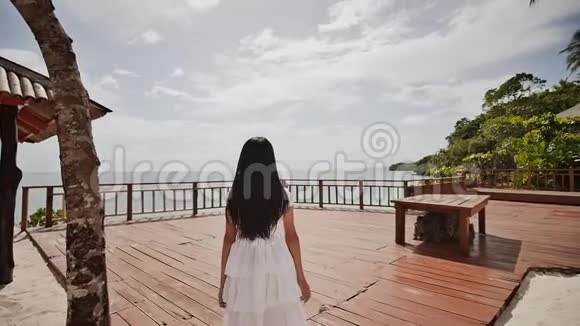 一个迷人的菲律宾女学生穿着白色的裙子在高台上俯瞰大海可怕的高度和视频的预览图