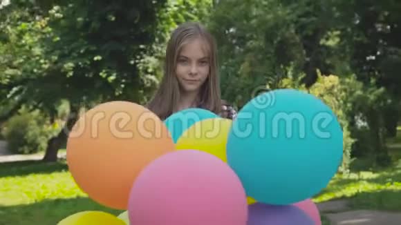 快乐的小女孩在公园里欢乐地旋转着五颜六色的气球视频的预览图