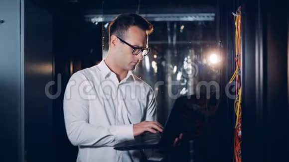 一个工程师IT专家类型的笔记本电脑在服务器房间关闭视频的预览图