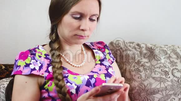 坐在沙发上看手机的女人视频的预览图