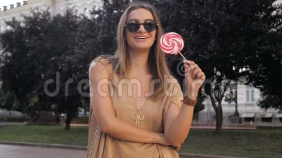 慢镜头视频快乐微笑的女人在公园里摆着大棒棒糖视频的预览图
