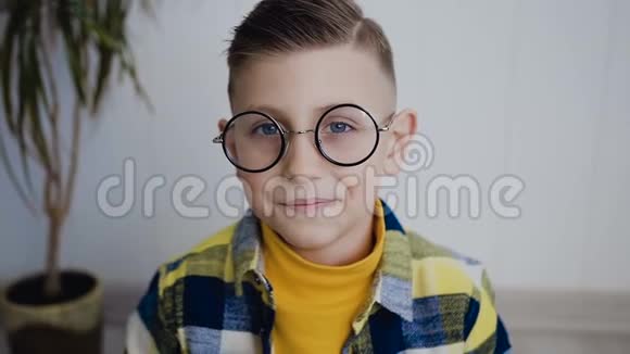 一个戴着蓝眼睛眼镜的英俊男孩看着相机用他读的一本书闭上了脸白色的视频的预览图