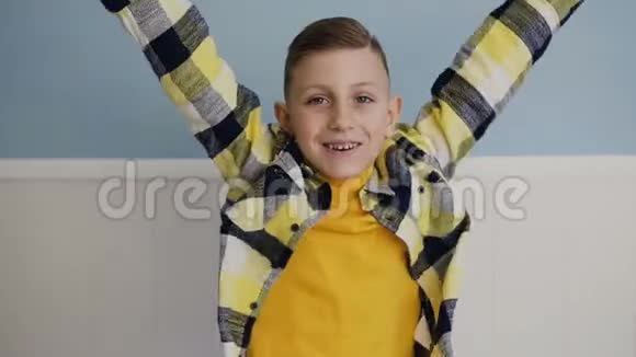 蓝眼睛漂亮的金发小男孩跳起来举起双手开心地笑着被孤立在白色背景上视频的预览图