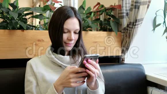 美丽的黑发女人在咖啡馆里用手机聊天微笑着视频的预览图