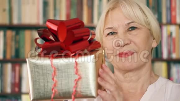 有礼物的高级女人领取养老金的人拿着红色丝带的金色礼盒庆祝生日视频的预览图