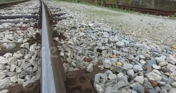 火车的铁轨包裹着草和从石头中生长出来的野花视频的预览图