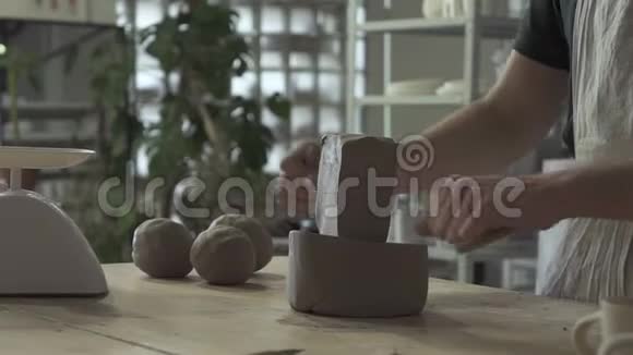 年轻的陶工正在用粘土工作站在室内的桌子旁视频的预览图