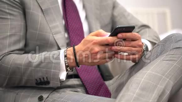 英俊的年轻商人用智能手机微笑快乐地穿着西装夹克使用智能手机的商人男子短信视频的预览图