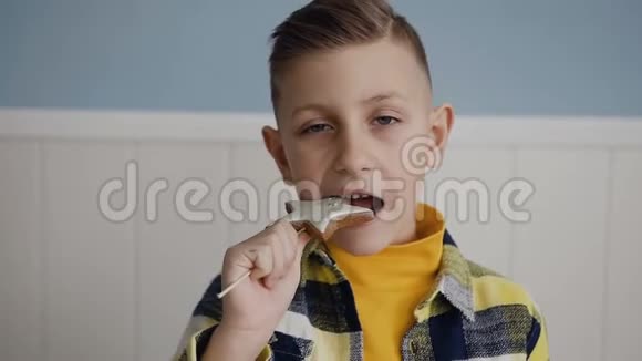 快关门一个英俊的金发小男孩吃的是美味的饼干在棍子上在白色背景上室内视频的预览图