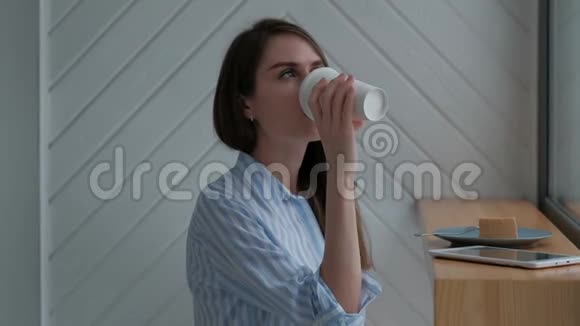 年轻时尚的女人在咖啡馆喝热拿铁吃奶酪蛋糕片视频的预览图