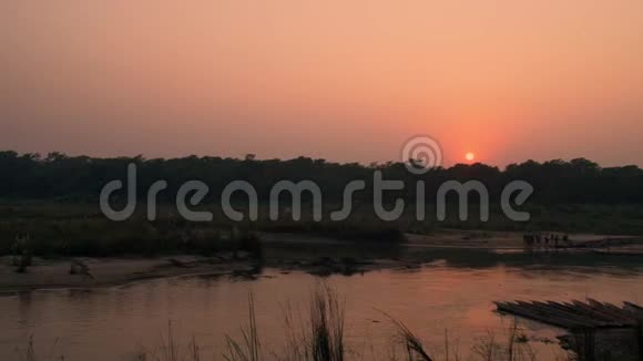 尼泊尔赤湾国家公园夕阳下的人们过河视频的预览图