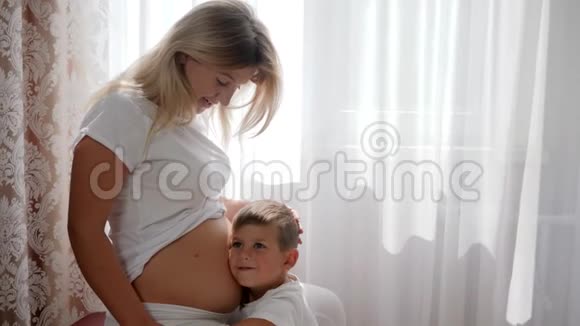 孩子抚摸孕妇的腹部在房间里微笑视频的预览图
