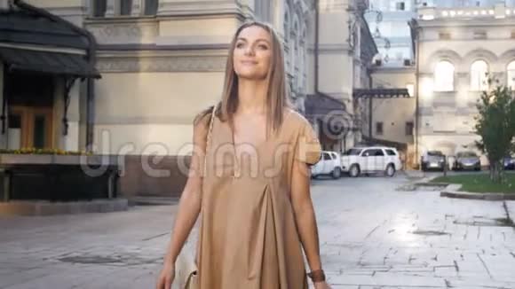4K镜头美丽微笑的女人在阳光明媚的日子走在老城区的大街上视频的预览图