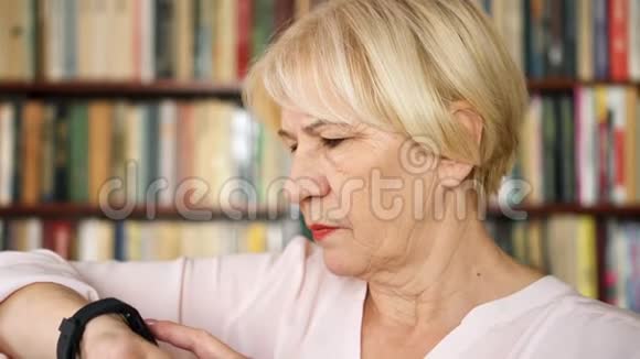 现代高级女性在家使用智能手表浏览阅读背景书架视频的预览图
