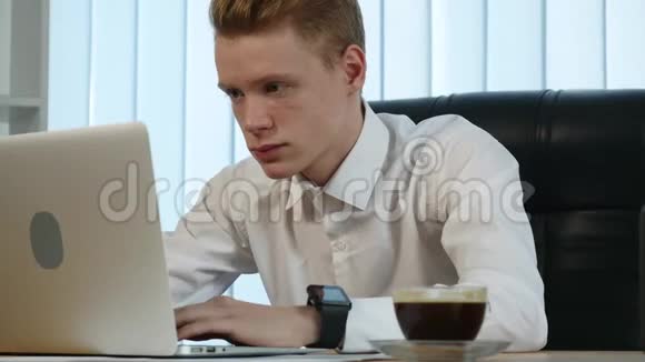 商人拿着笔记本电脑在办公桌上工作喝着咖啡周围都是大量的文件和财务视频的预览图