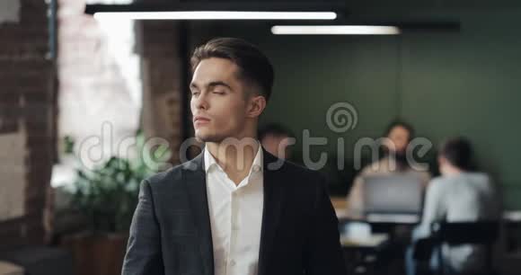 年轻成功商人在繁忙的办公室的肖像英俊的男员工看着相机微笑商务视频的预览图