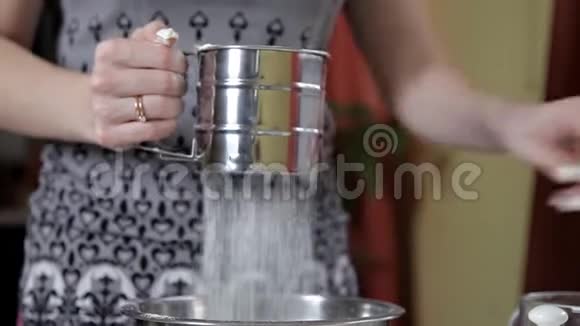 一个女人在厨房里用金属筛杯筛面粉烹饪和烘焙的概念视频的预览图