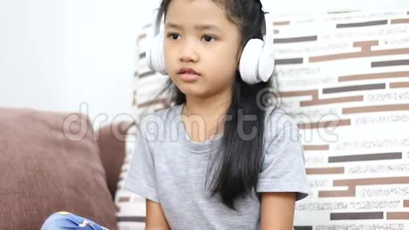 亚洲小女孩听音乐采用白色无线耳机技术移动应用理念视频的预览图