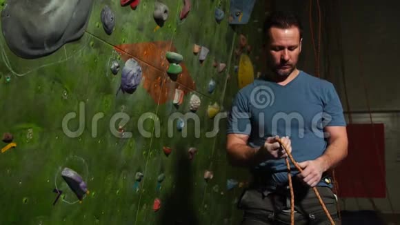 一名登山者在攀爬墙的背景下准备设备登山用编织结视频的预览图