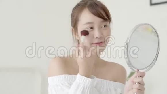 美丽的年轻亚洲女性用刷子刷镜涂粉美女用腮红化妆视频的预览图