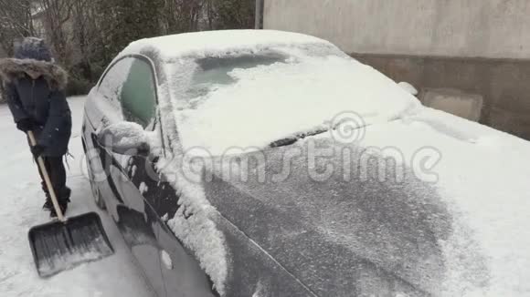 下雪时妇女在车周围除雪视频的预览图