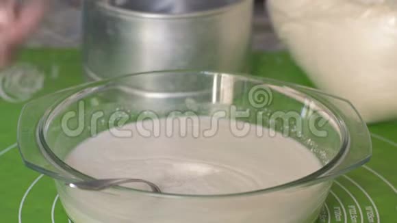 特写成熟的女人将糖勺放入玻璃器皿中加入面团和搅拌的配料视频的预览图