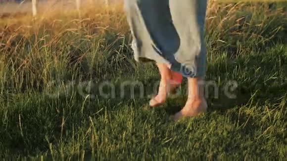 夏天年轻女子赤脚在高大的草地上行走视频的预览图
