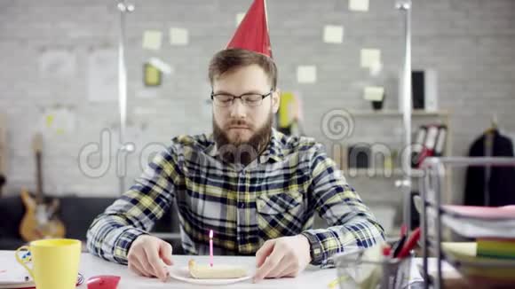悲伤迷人的商人在办公室庆祝孤独的生日他在一个小蛋糕上吹蜡烛他是视频的预览图