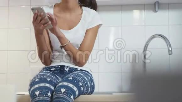 坐在厨房里用手机打字的年轻美国黑人妇女视频的预览图