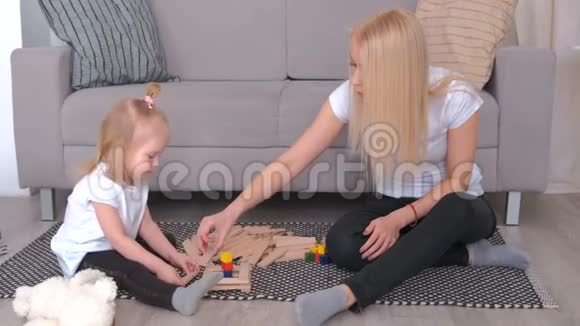 母亲和女儿用坐在沙发旁边地板上的木砖建造视频的预览图