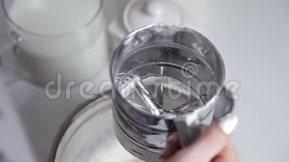 一个女人在厨房里用金属筛杯筛面粉烹饪和烘焙的概念视频的预览图