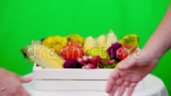 特写友好的握手在Chromakey绿色背景和一个盒子充满不同的蔬菜在工作室概念视频的预览图