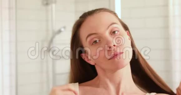 女人梳头看着镜头微笑视频的预览图