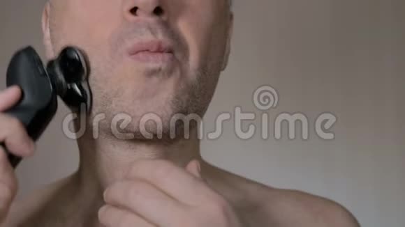 男人用电动剃须刀刮胡子特写镜头视频的预览图