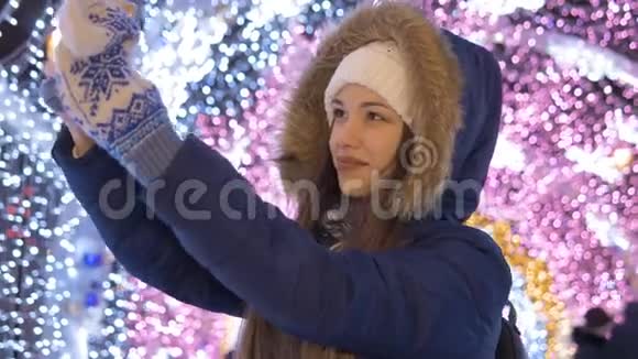 一个年轻女孩在智能手机上自拍在节日光照的背景下视频的预览图