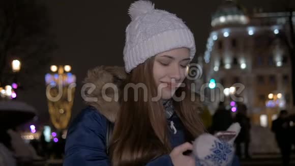 慢动作女孩在智能手机上写短信冬天在街上晚上视频的预览图