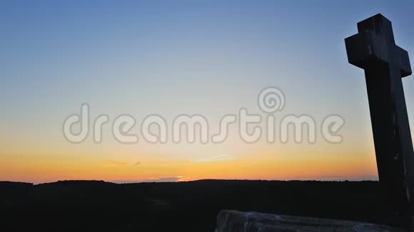 石横在山顶映衬着夕阳在日落背景上交叉日落时分山上的石堆视频的预览图