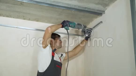 在室内施工现场使用电钻组装金属干壁型材的男性建筑工人视频的预览图