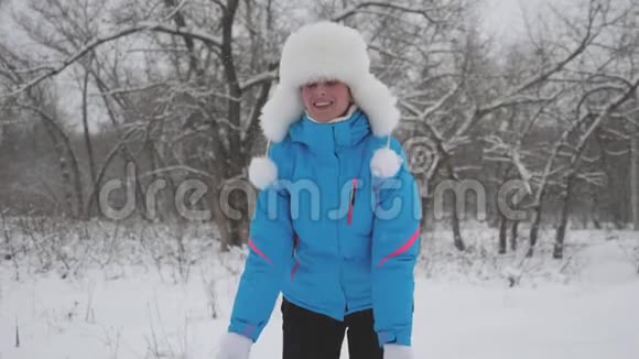 一个女人在冬天在公园里玩圣诞假期快乐的女孩举起手在森林里下雪视频的预览图